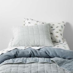 an unmade bed with blue and white sheets