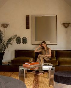 a woman sitting on top of a couch in a living room next to a mirror