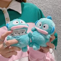 two blue stuffed animals are being held by a woman in pink pants and green shirt