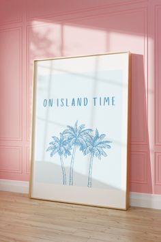 a framed poster with the words on island time in front of two palm trees against a pink wall