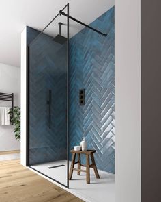 a bathroom with a blue tiled shower and wooden stool next to the walk in shower