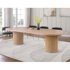 a large wooden table sitting on top of a rug in front of a white wall