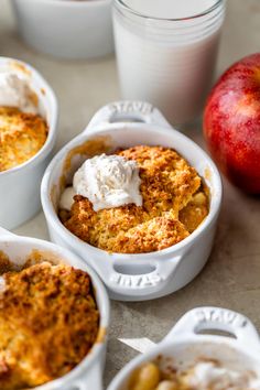 three white dishes filled with baked goods next to an apple