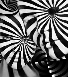 black and white photograph of two women with their faces painted like spirals in the center