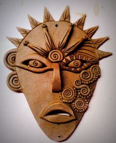 a wooden mask with an intricate design on it's face is shown against a white wall