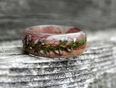 a close up of a ring on a wooden surface with plants growing out of it