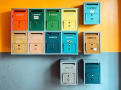 several mail boxes are arranged on the wall in front of an orange and blue background