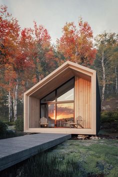 a small wooden cabin sitting on top of a lake next to trees with red leaves