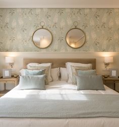 a bed with two mirrors above it and lamps on either side of the headboard