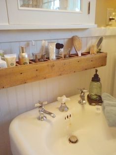 a white sink sitting under a window next to a wooden shelf filled with bathroom items