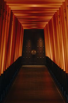 a long hallway with orange columns and lights on either side, leading to the ceiling