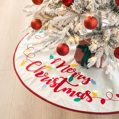 a white christmas tree skirt with red and green ornaments