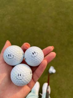 three golf balls with faces drawn on them in the palm of someone's hand