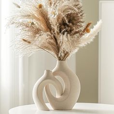 a white vase with some dried plants in it