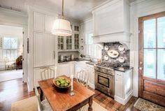 an image of a kitchen with white cabinets and wood table in front of the stove