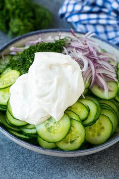 a bowl filled with cucumbers, onions and sour cream on top of it