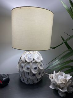 a lamp that is sitting on a table next to a vase with seashells