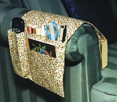 an animal print purse is hanging on the back of a green couch with books and magazines in it