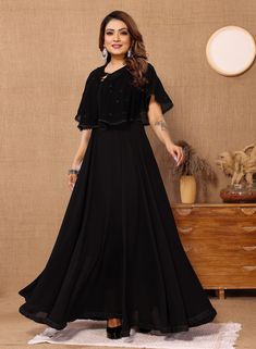 This elegant black long gown with cape is the perfect choice for a formal event or special occasion. Made from Georgette fabric with a Butter Crepe inner lining, this dress features a stylish Koti design and intricate lace work detailing, adding a touch of sophistication to your ensemble. The classic black color ensures versatility and timeless style, making it a must-have addition to your wardrobe. PRODUCT DETAILS :- Black solid maxi dress Round neck Short, flared sleeves Embellished detail Max Black Fitted Gown With Cape Sleeves, Black Gala Dress With Cape Sleeves, Black Evening Gown With Cape Sleeves, Georgette Maxi Dress For Evening, Georgette Maxi Evening Dress For Formal Occasions, Evening Georgette Maxi Dress, Formal Georgette Maxi Length Evening Dress, Formal Maxi Length Georgette Evening Dress, Evening Maxi Dress In Georgette