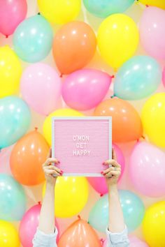 a person holding up a sign in front of balloons