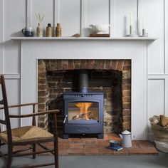 a wood burning stove sitting inside of a living room next to a chair and table