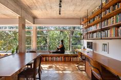 a woman sitting on a bench in front of a book shelf filled with lots of books