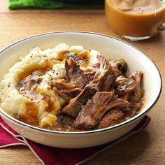 a bowl filled with meat and mashed potatoes next to a glass of orange juice