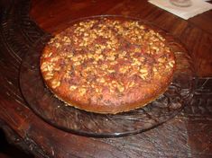 a cake sitting on top of a wooden table next to a glass plate filled with nuts