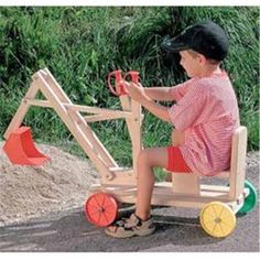 a young boy is playing with a wooden toy tractor on the road in front of some grass