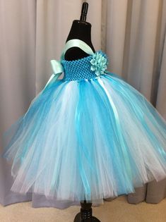 Fuzzy Duckling Design dresses ~ handcrafted for the little princess in your life. Our beautiful flower girl dresses feature a stretchy, crocheted bodice that is fully lined for both comfort and modesty. These extra full skirts sparkle and shine with four layers of high quality tulle in matte, shimmer, and glitter finishes. Satin ribbons and flowers are added to make each dress something special. To determine the length of dress to order: measure from where the top edge of the bodice will start ( Fitted Blue Tutu Dress For Wedding, Blue Princess Dress With Tulle Skirt For Wedding, Blue Tulle Tutu Dress For Pageant, Cute Blue Princess Dress For Pageants, Cute Blue Princess Dress For Pageant, Light Blue Fitted Tutu Dress For Wedding, Fitted Light Blue Tutu Dress For Wedding, Whimsical Blue Fitted Tutu Dress, Blue Tulle Tutu Dress For Dress-up