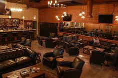 a large room with couches, tables and chairs in front of a bar filled with liquor bottles