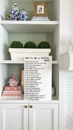 a white book shelf filled with books and vases on top of eachother