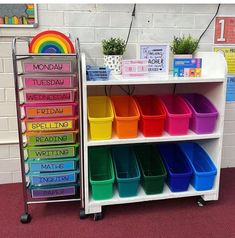 there is a book shelf that has many different colored bins on top of it