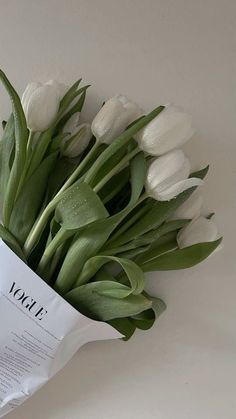 a bouquet of white tulips is wrapped in paper