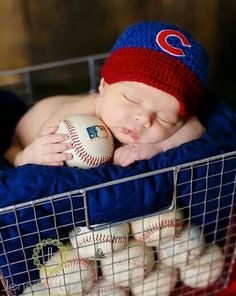 a baby is sleeping in a basket with baseballs