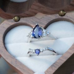 two engagement rings in a heart shaped wooden box with white and blue stones on it