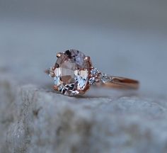 a close up view of a ring with an oval shaped morganite and two smaller round diamonds