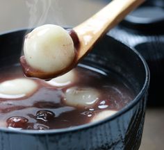 a wooden spoon with some food in it and steam coming out of the pot,