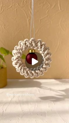 a crocheted ornament hanging from a string with a video in the center