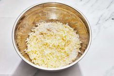 a metal bowl filled with cheese on top of a white counter