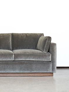 a gray couch sitting on top of a hard wood floor next to a white wall