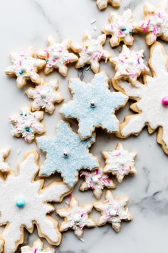 decorated sugar cookies on a marble countertop with sprinkles and frosting