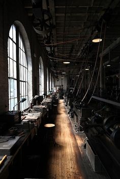 an industrial looking room with lots of windows and wood flooring on both sides of the room