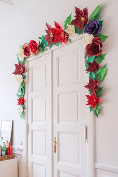 paper flowers are hanging on the wall next to two white doors with one open and another closed