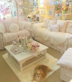 a living room filled with lots of white furniture and flowers on the table in front of it