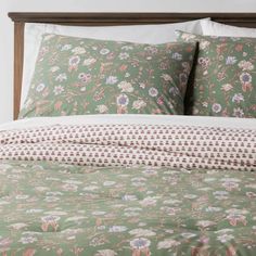 a bed with green and pink floral bedspread, pillows and pillowcases