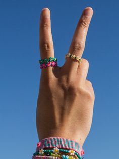 a person's hand making the peace sign with beaded bracelets on it