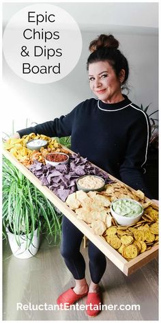 a woman holding a tray with chips and dips on it