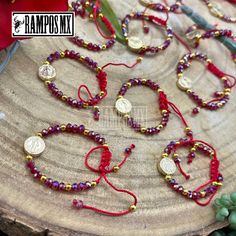 three bracelets with red string and gold beads on top of a piece of wood