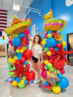 a woman standing next to a large balloon sculpture in a room filled with balloons and confetti